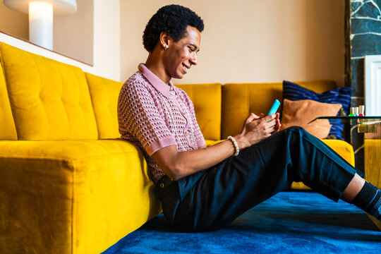 Fluid gender young man wearing cross dressing clothing at home, LGBTQ and diversity concepts - Hispanic non binary male portrait in a colorful apartment, LGBT people concepts - Powered by Adobe