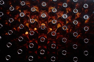 Top view of bottlenecks of brown glass bottles at production line in craft beer or cider factory