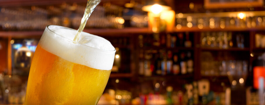 pouring beer into glass on bar background