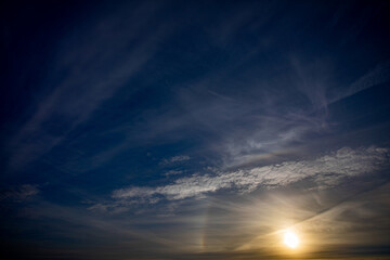Experience the breathtaking beauty of a sunset painting the serene sky with wispy clouds