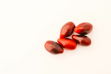 Minimalistic arrangement of fresh cornelian cherries on a white background. A clean and simple composition emphasizing the vibrant red color and smooth texture of the berries