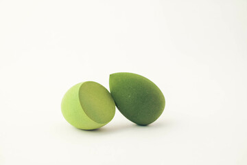 Green makeup sponges on a white background. A minimalist composition showcasing beauty tools for foundation blending, perfect for skincare and cosmetics themes