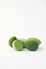 Green makeup sponges on a white background. A minimalist composition showcasing beauty tools for foundation blending, perfect for skincare and cosmetics themes