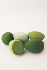 Green makeup sponges on a white background. A minimalist composition showcasing beauty tools for foundation blending, perfect for skincare and cosmetics themes