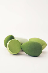 Green makeup sponges on a white background. A minimalist composition showcasing beauty tools for foundation blending, perfect for skincare and cosmetics themes