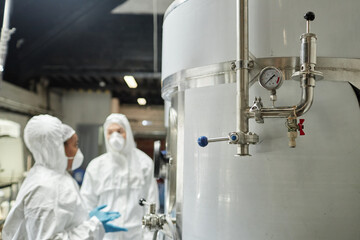 Close up on pressure gauge and pipes on stainless steel tank in workshop of food or chemical factory, copy space