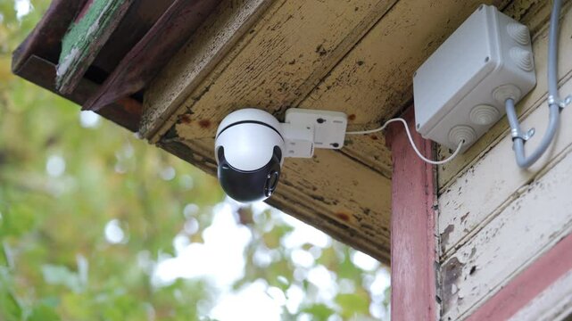 Security outdoor PTZ surveillance camera installed under the roof of the house. Pan tilt zoom camera provide HD view zoom and 360 rotation for full security coverage.