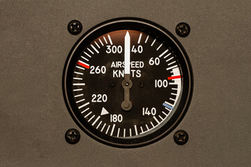 Airspeed Indicator. An analog instrument in the flight deck of an airplane. A dial with needle and numbers display the velocity of an aircraft to a pilot in the cockpit