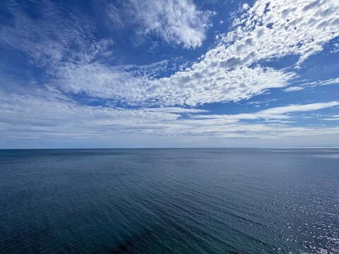 Sea wide blue calm water and heavenly sky clouds