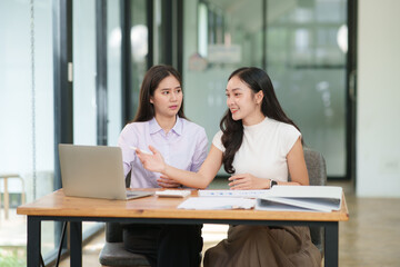 Obraz premium Businessman, two Asian women give advice, discuss work, documents on laptop at office