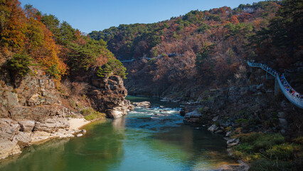 Autumn scenery of the Hantan River Columnar Joint Road, with canyons and cliffs formed by the river flowing through the volcanic terrain. (emerald water, blue sky and colorful leaves)