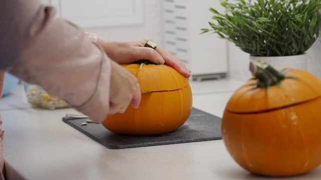 Woman preparing stuffed red kuri squash in the kitchen. Stuffed orange colored winter squash for baking in the oven.