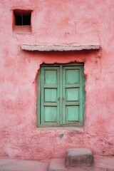 Fototapeta premium A pink building with a green door and window