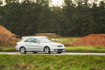 A Car Driving Fast on a Curvy Road with a Stunning Sunset and Forest