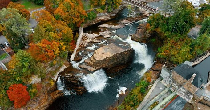 Aerial view on Ausable Chasm waterfall, Adirondack mountains in autumn colors, upstate New York. Hydroelectric power station buildings on the bank of the river.