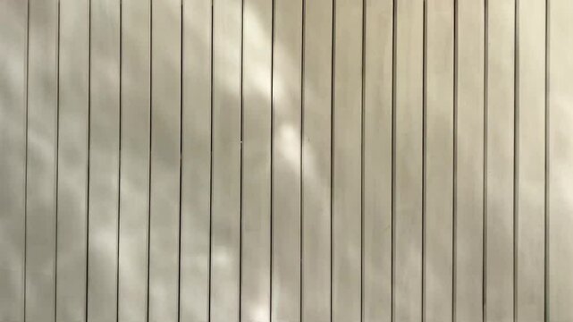 Closeup of water reflection and sun light on striped wall. Sun reflection of water pool on striped wall partition.  Swaying shadow of sun reflection from pool on wall. Sun reflection backgroud video.