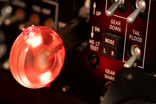 Illuminated red landing gear handle. Switches and lights in the cockpit of a large passenger aircraft. Red signals warning to the pilots. Landing gear is in transit and unsafe