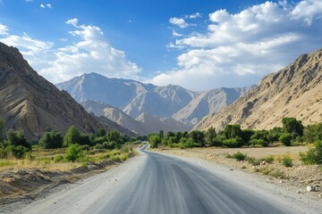 Fototapeta premium Scenic mountain road winding through valley, lush greenery, blue sky