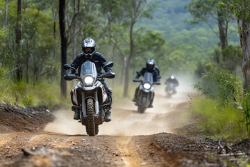 Obraz premium Motorcycles riding on dirt trail through forest, dust clouds, adventure