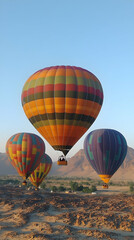 Fototapeta premium Colorful hot air balloons ascend over a desert landscape.