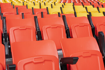 Fototapeta premium Empty red and yellow seats in the stadium stands