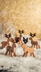 Naklejka premium Festive winter scene featuring handcrafted wooden reindeer toys standing on white snow with a luxurious golden bokeh background.