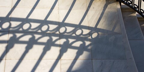 Fototapeta premium Decorative shadow pattern on tiled floor from a metal railing