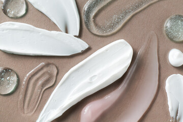 Smears of different cosmetic products on grey background, flat lay