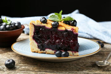 Slice of homemade blueberry pie on wooden table, closeup