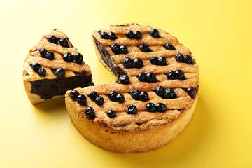 Cut homemade blueberry pie on yellow background
