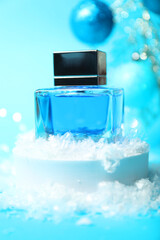 Christmas composition with perfume bottle and snow on light blue background, closeup