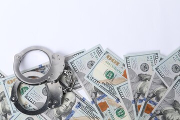Corruption concept. Handcuffs and dollar banknotes on white background, top view