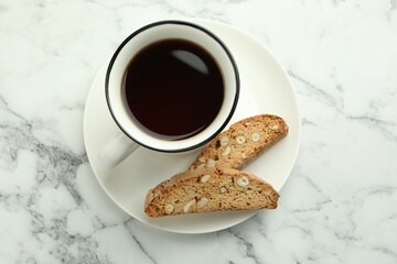 Traditional Italian almond biscuits (Cantucci) and cup of coffee on white marble table, top view
