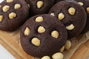 Tasty chocolate cookies with hazelnuts on white table, closeup