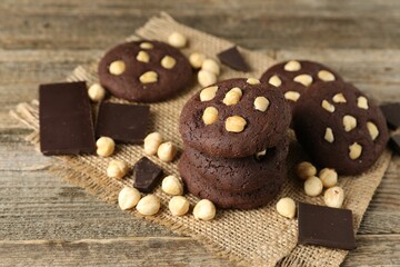Tasty chocolate cookies with hazelnuts on wooden table, closeup
