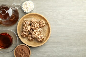 Tasty chocolate puffed rice balls served with tea on wooden table, flat lay. Space for text