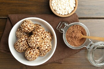 Tasty chocolate puffed rice balls and ingredients on wooden table, flat lay