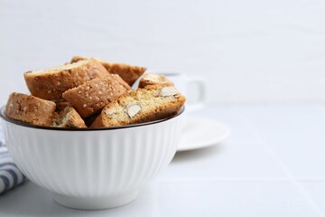 Traditional Italian almond biscuits (Cantucci) in bowl on white table, closeup. Space for text