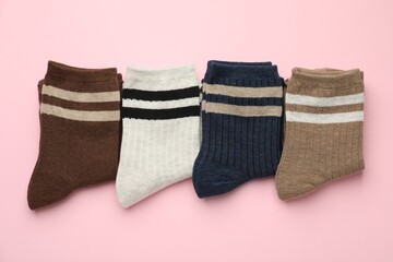 Different comfortable socks on light pink background, flat lay