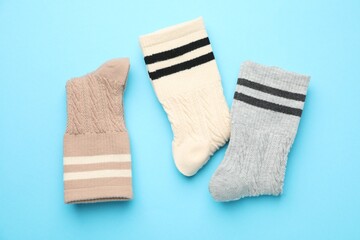 Different comfortable socks on light blue background, flat lay