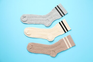 Different comfortable socks on light blue background, flat lay