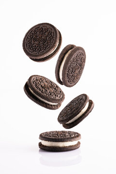 Delicious Oreo biscuits with chocolate and cream on white background