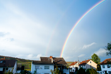 Panoramic view of rainbow with dark clouds over houses after a rainstorm