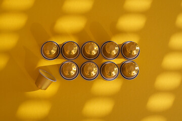 Capsules of coffee under sunlight on a yellow background. Top view, flat lay