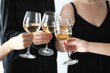 People clinking glasses of wine indoors, closeup