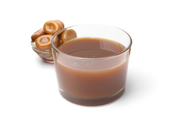 Tasty caramel sauce in glass bowl and candies isolated on white