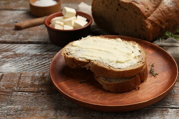 Fresh bread with butter on wooden table, closeup