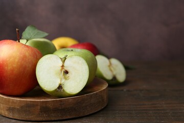 Different ripe apples on wooden table, closeup. Space for text