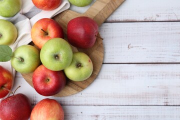 Different whole ripe apples on white wooden table, flat lay. Space for text