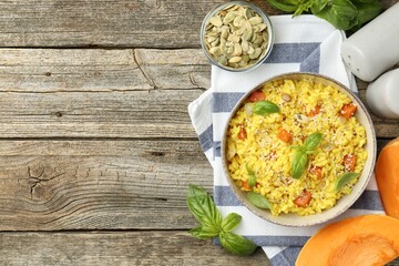 Delicious pumpkin risotto served on wooden table, flat lay. Space for text